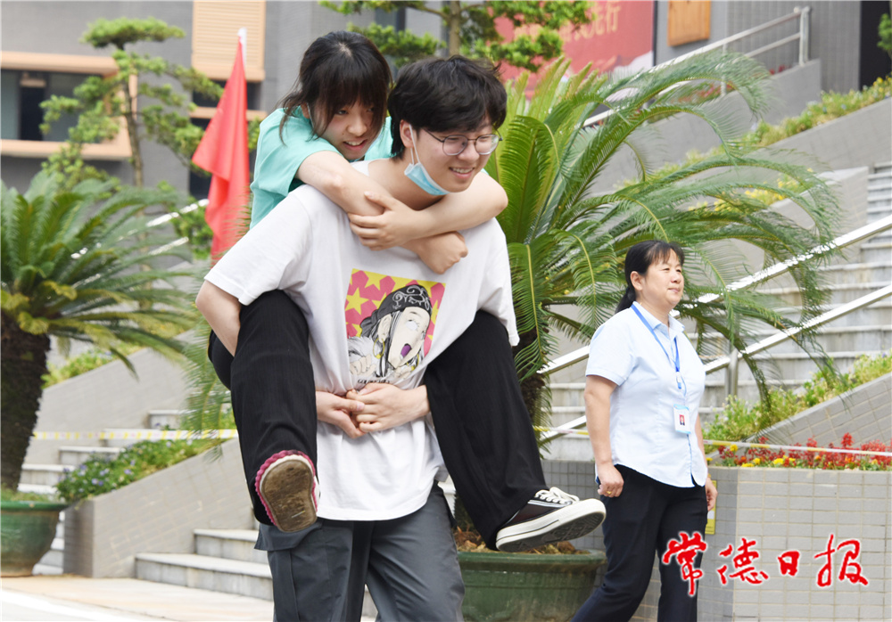 6月8日，普通高等學(xué)校招生全國統(tǒng)一考試湖南省澧縣第二中學(xué)考點，一名男考生背著腳部受傷的女考生走向考場。             柏依樸  何祖華 攝.jpg