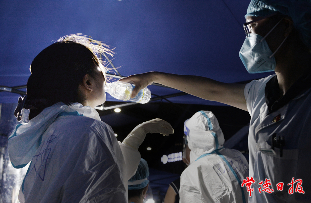 09 8月1日19時(shí)起，武陵區(qū)穿紫河街道在市體育中心設(shè)立臨時(shí)核酸采集點(diǎn)，每日6時(shí)至22時(shí)對(duì)群眾開(kāi)放。圖為天氣炎熱，醫(yī)護(hù)人員相互喂水解渴。 本報(bào)記者 徐珊珊 攝_副本.jpg